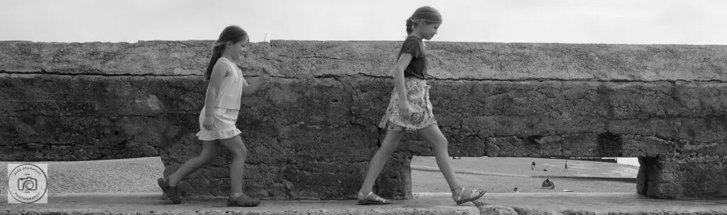 Sisters walking along beach groin