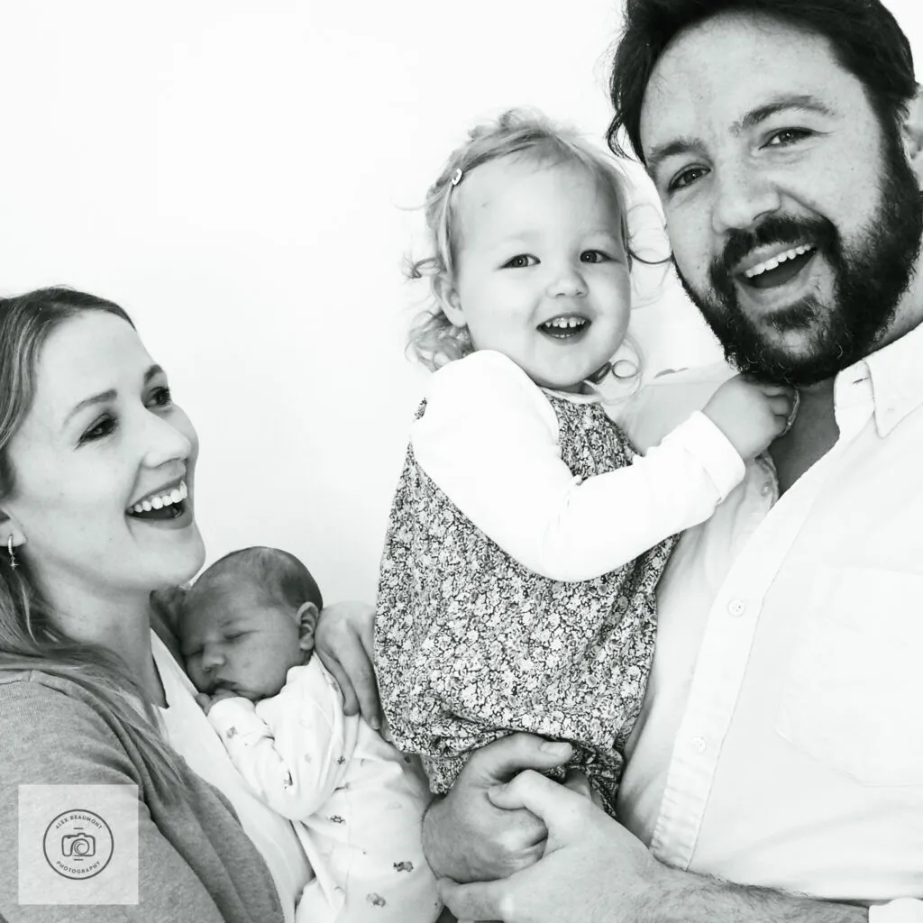 newborn photoshoot at home, Dad holding toddler and mum holding newborn