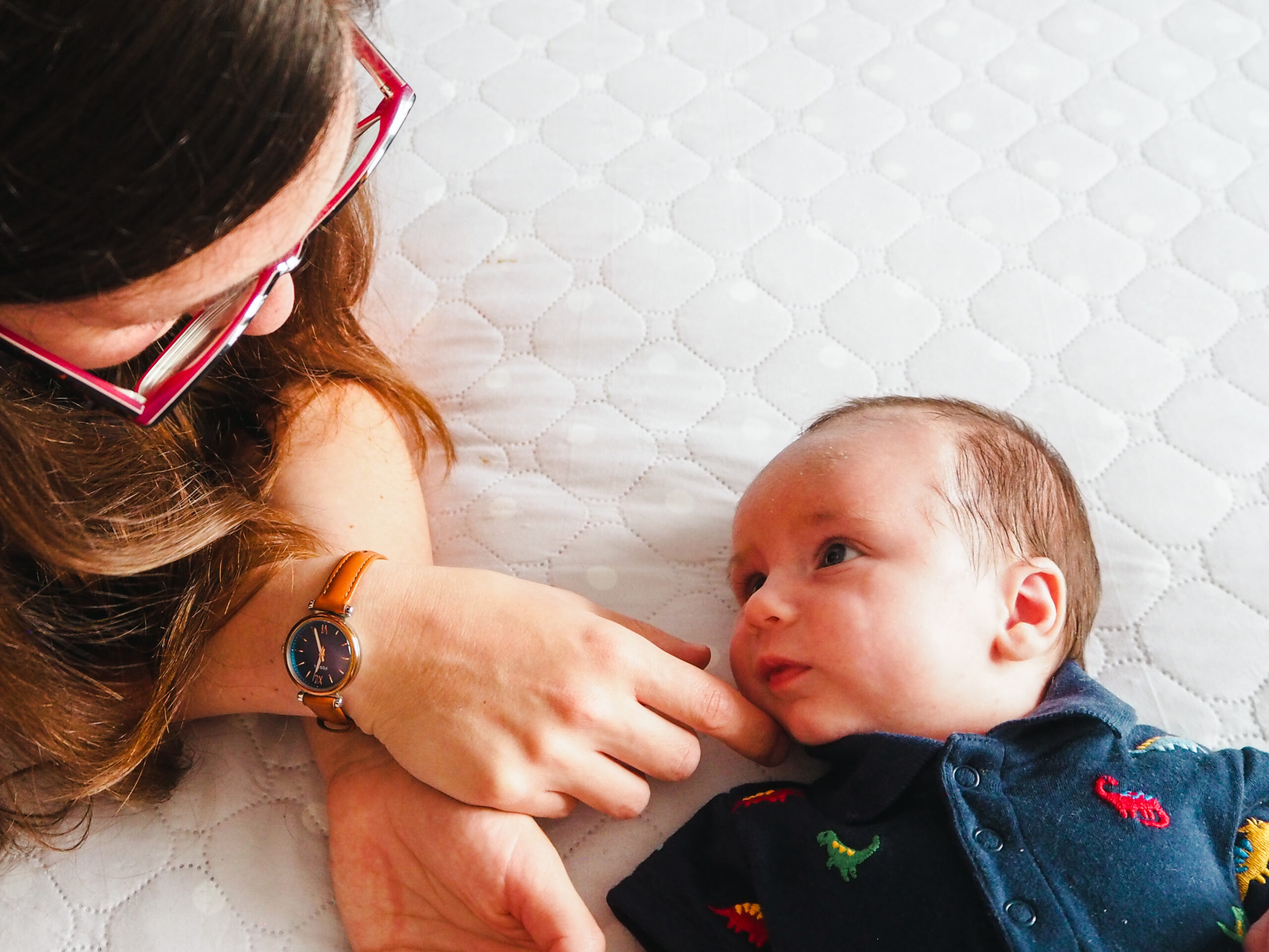 Newborn lying on bed looking at mum