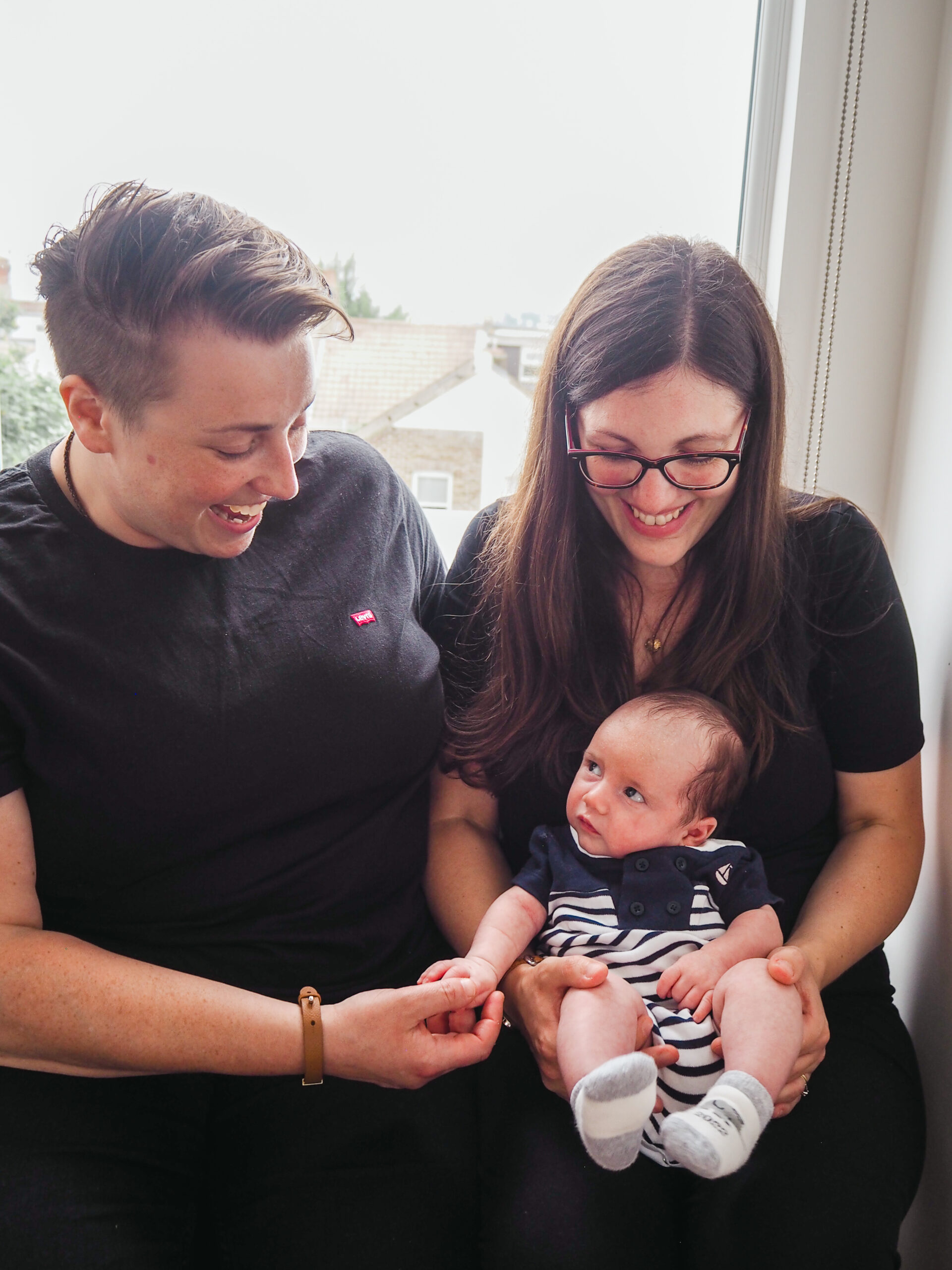 Mum holding newborn in window and mum holding baby's hand